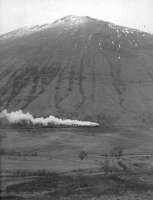 Caption by Colin McDonald. The West Highland Railway, c. 1960. This was taken by my brother Malcolm McDonald who now lives in Calgary, and he sent it to me last week when we were discussing my recent trip to Rannoch. He took it on a cycling holiday one Easter, in between driving hail storms. He can't remember the exact year, but suggested 1960, plus or minus 2 years. He thought there were two Stanier Black 5s pulling the train south. The train is on the slopes of Beinn Dorain, approaching the Horseshoe Curve and County March Summit.<br><br>[Malcolm McDonald //1960]