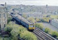 EMU 303077 on a Cathcart Inner Circle service at Pollockshaws East station on the 9th of November 1978. Today it is reduced to a <b>Bus Shelter</b>. The Church tower is at the corner of Kilmarnock Road and Newlands Road.<br><br>[Ian Millar 09/11/1978]