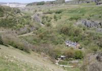 Panoramic view of the old triangle at Blackwell Mill, taken from the lay-by on the A6 road that runs high above this point. Top left is the Great Rocks quarry complex and the surviving line from there to Buxton curves north to west. The old main line runs behind the railway cottages down to Millers Dale while the west to east chord is at the foot of the picture, now part of the Monsal cycling trail. It is on this chord that Blackwell Mill Halt, claimed for many years to be the smallest station in Britain, is situated but just out of view. The Disused Stations website advises that the two short platforms are still in situ and has pictures of the halt when open.<br><br>[Mark Bartlett 07/05/2017]