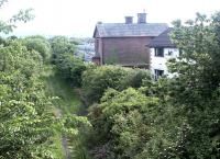 The Port Road looking west through Maxwelltown towards Stranraer in May 2003, with the line having reverted to nature. Part of the fuel distribution depot can just be seen beyond the station building in the former yard. Plans were already underway to turn the route into the 'Maxwelltown Railway Path' [see image 15526].<br><br>[John Furnevel 27/05/2003]