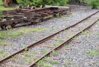 An example of Decauville track on the ground at Skyttorps Maskinmuseum in Central Sweden. Consisting of portable sections of rails with bolted-on sheet metal sleepers, this can be laid directly on most types of ground surface including peat bogs without the need for a formation (track bed) or even ballast. Here the ballast is provided by locally occurring crushed rock. For more typical surface conditions [see image 59809].<br>
 This system provides a quick and easy method of laying 600mm narrow gauge track for light rail in 'short term' use. It was used extensively on the trench railways of the Western Front during the Great War.<br><br>[Charlie Niven 17/06/2017]