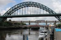 Seen beyond the deck of the Tyne Bridge a Northern Class 156 Sprinter, on a short working from Newcastle to Metro Centre, sets out across the High Level Bridge on 26th June 2017. Built in 1928 the classic Tyne Bridge was restored to its original green colour (with liberal splashes of white Kittiwake guano) in the 1980s after many years painted in blue and red.<br><br>[Mark Bartlett 26/06/2017]