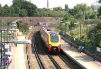 The 14.22 Brighton - Birmingham - Manchester Piccadilly Virgin CrossCountry service runs through platform 4 on the WLL side of West Brompton station in July 2005 as a District Line train on its way up the hill from Fulham Broadway approaches the adjacent London Underground platforms. The Voyager will call at Kensington Olympia on its way across west London. <br><br>[John Furnevel 22/07/2005]