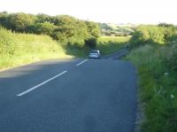 A large depression exists along Ellerby Lane, on the edge of Runswick Bay Top village, at the location where the coast line through Staithes to Whitby West Cliff crossed over the lane approx 1Km south east of Hinderwell Station. The trackbed is only slightly above the road level on the Runswick side approach, so could possibly have crossed the road on the level, rather than the road being cut away to pass below the line. The view is looking south west towards the A174 and Ellerby village, with the Runswick boundary stone just to rear of view. <br><br>[David Pesterfield 18/06/2017]