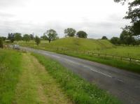 Shortly after leaving the East Coast main line at Cordio Junction the line to Leeds via Ripon and Harrogate crossed the A167 road south of North Otterington village before reaching the first station south at Newby Wiske. The view looking south shows a section of the lengthy stretch of embankment that runs south west from the former rail overbridge towards Newby Wiske. The approach from the north was mostly on the level or a shallow embankment, and the short built up section just before the bridge has been profiled down some 10m back from the road. Nothing remains of the bridge, where a vehicle can be seen parked where an abutment would have been.<br><br>[David Pesterfield 17/06/2017]