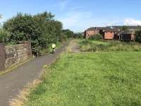 View west along the remains of the island platform at Scotstoun East. The cyclist is passing the site of the station exit.<br><br>[Colin McDonald 12/07/2017]