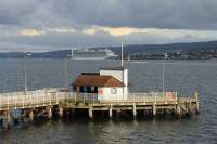 Kilcreggan Pier, with its surviving signalling tower, on 30th July 2017. In the background the 112,000T <I>Caribbean Princess</I> departs Greenock on a British Isles cruise, next stop Invergordon.  <br><br>[Mark Bartlett 30/07/2017]