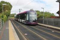The modern tram stop at Rossall Square has been shoehorned in between the houses and there are no shelters or seating on the narrow platforms. <I>Flexity</I> 007, heading for Blackpool, slows to call on 12th August 2017.<br><br>[Mark Bartlett 12/08/2017]