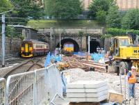 View from the west end platforms at Waverley towards the Mound tunnels at noon on Thursday 5 July 2007, with platform works in full swing. A ballast train is leaving the scene via the central tunnel heading back to Millerhill, with EWS 66205 bringing up the rear. On the right a roadrail machine is in action, while over on the left ScotRail 156514 is passing the west box at the start of its journey to Glasgow Central. On the terrace below the National Gallery a young mum is taking advantage of the free show to administer lunch to junior.<br><br>[John Furnevel 05/07/2007]