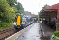 In bucketing rain a 380104 draws to a stop at West Kilbride. Although out of use the station building still stands, but nothing appears to remain of the former up platform.<br><br>[Ewan Crawford 17/08/2017]