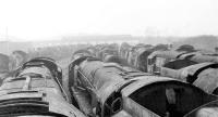 Row upon row of Bullied Pacifics, and a few other classes too, stand in Woodhams scrapyard in Barry in October 1975. In the background a Valleys suburban DMU crosses to Barry Island. Later rescued, a number of these locos would subsequently take part in the 2017 50th Anniversary galas commemorating the end of Southern Steam. <br><br>[Mark Bartlett 28/10/1975]