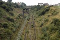 Six years after closure, the track layout at Prospect Hill Junction appears to be intact but the signal box is very much the worse for wear! View looking north from an accommodation bridge near Airy Hill Farm towards the bridge carrying the A171 Middlesborough to Whitby road over the line. The connecting chord to the Esk Valley line is on the left. 21st August 1971.<br><br>[Bill Jamieson 21/08/1971]