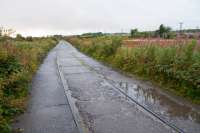 This was one of the lines serving the Nobel Explosives site at Ardeer. It was concreted over to provide road (and retain rail) access to the site from the north east, thus preserving the line.<br>
<br>
The branch originally served Misk Colliery No1, Bogend Pit and a chlorine works.<br>
<br>
The branch closed when severed by the A78 dual carriageway. Track on this section was, not surprisingly, left in place. This is the view west towards the works, with the A78 on the right.<br><br>[Ewan Crawford 07/09/2017]