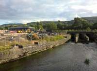 I visited Aberdare to photograph the curious layout in the old High Level goods yard, where tarmac had been laid up to rail level, and industrial units had their brick side walls built across the rails. It looked as though the determined goods yard rambler would have to knock on doors to ask the local entrepreneurs' permission to walk through their industrial units. But things have changed; the whole goods yard area is now a car park for the local college. The width of the piers for the river bridge North of the station, however, show that here was once a fan of tracks here. Notice the new roof on the station building (left). View looks south. [Ref query 1 October 2017]<br><br>[Ken Strachan 19/08/2017]