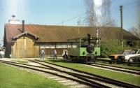 A steam outline diesel tram locomotive stands outside the shed and workshops of the Chiemsee-Bahn at Prien-Stock in Bavaria. The photo was taken in April 1989 and at the time, the station of this short narrow gauge line was to the left. It is understood that the shed in this photo was demolished in 2011 and replaced with a new building and station. The station is next to a pier for ferries sailing on Chiemsee, including to Herreninsel and island where the palace of Herrenchiemsee is situated. The palace was built for King Ludwig II of Bavaria and is based upon the palace of Versailles.<br><br>[John McIntyre /04/1989]