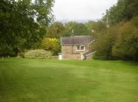 Looking north to Ryedale Lodge, the former Ryedale Lodge Hotel, now a private house formed out of the former Nunnington Station. Tree growth over the years is obscuring more of the property compared to earlier views. A deep cutting exists on either side of the road bridge, but, due to the land contour, the platform was sited beyond the cutting north end.<br><br>[David Pesterfield 24/09/2017]