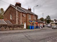 The street aspect of the station building at Maybole looks a good deal more<br>
welcoming than the platform side. At the far end is the former ticket<br>
office with lights on inside making it look like it's still open. In fact<br>
it's a Network Rail office.<br>
<br><br>[David Panton 10/10/2017]