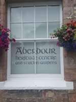 A window at the Aberdour Heritage Centre, flanked by hanging flower baskets.<br><br>[John Yellowlees 27/07/2017]