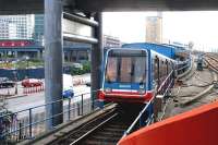 View west from Poplar station on the Docklands Light Railway in the summer of 2005, with a train leaving the platform destined for Tower Gateway.   At the upper left of the photograph, on the other side of West India Dock Road, another DLR train is standing at the platform of West India Quay station with a service to Stratford. <br><br>[John Furnevel 21/07/2005]