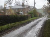 Looking north west along Rape Lane to the former Pockley Gates Crossing Keepers houses sited around mid-way between Helmsley and Nawton stations. The track ran across where the entrances can be seen forward of the houses. The A170 road from Helmsley to Kirkbymoorside can be seen in the near distance.<br><br>[David Pesterfield 20/11/2017]