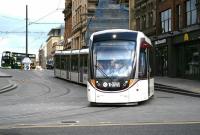 An Edinburgh tram about to make a 'ninety right' from South St Andrew Street onto Princes Street on its way to the airport on 13 July 2017. In the background a Lothian 43 bus is about to complete a similar manoevre on St Andrew Square at the start of its journey to South Queensferry.<br><br>[John Furnevel 13/07/2017]