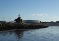 The old Harbour station in Morecambe on a sunny 7th January 2018. Rock armour sea defences now surround the jetty on which it stands but steamers could tie up alongside the building when the station was open. The famous Art Deco styled Midland Hotel, built by the LMS, can also be seen with the old Morecambe Promenade station just visible behind that.<br><br>[Mark Bartlett 07/01/2018]