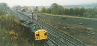 The view to the east from the West Road (former A69) bridge. The Class 37 loco has just propelled an engineers train into the sidings to the west of Haltwhistle Station. The former yard to the south of the station was still visible from the bridge. The Alston Branch viaduct over the South Tyne is in the background in the autumn murk. For a view of the loco to the west of this bridge [see image 62558].<br><br>[Charlie Niven /10/1989]