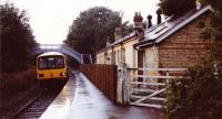 The Class 143 Pacer unit sits at the platform on a wet Sunday afternoon in Weardale. There was time to take a few photos while waiting to return to Darlington from where the train continued to Saltburn. This station has now been restored to its former state by the Weardale Railway.<br><br>[Charlie Niven /08/1989]