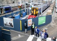 View from the station walkway at Waverley on 8 February 2018, with traincrew, passengers, catering staff and British Transport Police all going about their business. At the recently extended platform 12 is the 1027 to Glasgow Central, while the train at 11 is the 1030 to Glasgow Queen Street. Although it will leave 3 minutes later, the latter service will reach its destination 28 minutes earlier than the former.<br><br>[John Furnevel 08/02/2018]