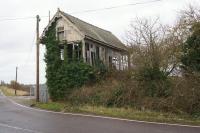 Although the station building has been converted into domestic accommodation, the signal box on the other side of the former level crossing at Postland has not been so fortunate. With slates missing from the roof, most windows broken and ivy taking hold it looks like it may not survive much longer when seen on 20 February 2018. A slight surprise was that the McKenzie & Holland lever frame was still in place.<br><br>[John McIntyre 20/02/2018]