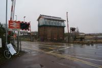 The March East Junction signalbox and level crossing with the station to the left of this view on a very dull and wet 19th February 2018.<br><br>[John McIntyre 19/02/2018]