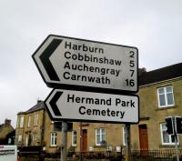 '... Carstairs Junction and Lanark.' This road sign near West Calder station is a neat listing of the closed stations on the Midcalder Junction to Carstairs section. Cobbinshaw is perhaps an odd choice as a road destination when the comparative metropolis of Woolfords is nearby. Cobbinshaw is an unmarked couple of houses at the end of an unsignposted lane. Good spot for reservoir fishing though, if you like that sort of thing.<br><br>[David Panton 15/03/2018]