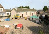 Work in progress on new and refurbished housing at the south end of Kinross in May 2005 includes part of the former Loch Leven station. The main building on the up side is shown here, with part of the down side (white) structure visible through the gap to the left. The smaller building to the right, which stood at the north end of the up platform, was being used by a local plumber [see image 61338]. The station closed to passengers in 1921, with the line closing completely in 1970. View is north west from a point alongside the B996 road.<br><br>[John Furnevel 28/05/2005]