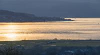 A view from the Carman hill. A northbound for Oban and Mallaig has passed Cardross and is now passing the the numerous level crossings just to the west. Gourock and Dunoon can be seen in the background.<br><br>[Ewan Crawford 26/03/2018]