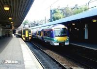 Platforms 3 and 4 at Haymarket station on a bright and sunny May morning in 2004. A Glasgow shuttle has just made its first stop after leaving Waverley, while a 158 is about to disappear into Haymarket Tunnel with a Bathgate - Newcraighall service.<br><br>[John Furnevel 14/05/2004]