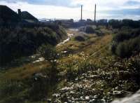 The approach to Ardrossan North, now houses. Left to right; coal yard (in use in 80s), station and locomotive shed. In the distance is the Shell refinery.<br><br>[Ewan Crawford //1987]