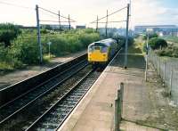 A 26 and two 37s heading east through Holytown with a very long iron ore train for Ravenscraig.<br><br>[Ewan Crawford //1987]