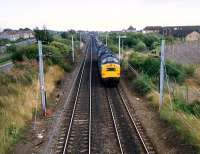 Looking east to Holytown station and beyond Holytown Junction. Two 37s and a 26 run back having taken a long iron ore train to Ravenscraig.<br><br>[Ewan Crawford //1987]