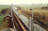 An express heading south at Strawfrank Junction passes a Ravenscraig limestone train on its way north.<br><br>[Ewan Crawford //1988]