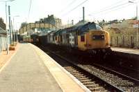 Ravenscraig-Hunterston iron ore empties passing a Glasgow train at Johnstone.<br><br>[Ewan Crawford //]