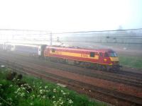 Having brought 15 sleeping cars overnight from Euston as far as Carstairs, EWS 90028 stands well to the north of the platform at 0625, shrouded in fog, while the rear seven coaches are detached for Edinburgh. 90028 will then proceed to Glasgow Central with the remainder.<br><br>[John Furnevel 06/06/2006]