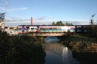 The morning sun catches an Aberdeen - Inverness service at Mosset Road level crossing on the eastern approach to Forres station in November 2005.<br><br>[John Furnevel 04/11/2005]