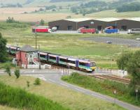 A Perth - Edinburgh Waverley train photographed southbound over Blackford level crossing in June 2005. The large 'Highland Spring' bottling plant stands in the background.<br><br>[John Furnevel 21/06/2005]